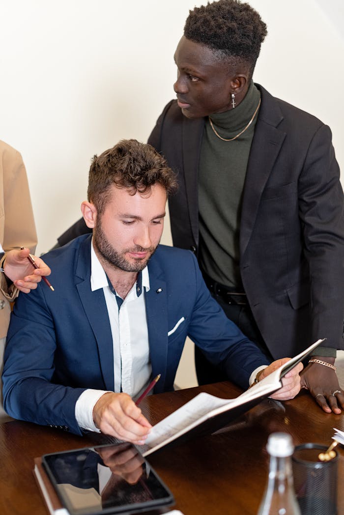 Two professionals discussing documents during a business meeting in an office setting.